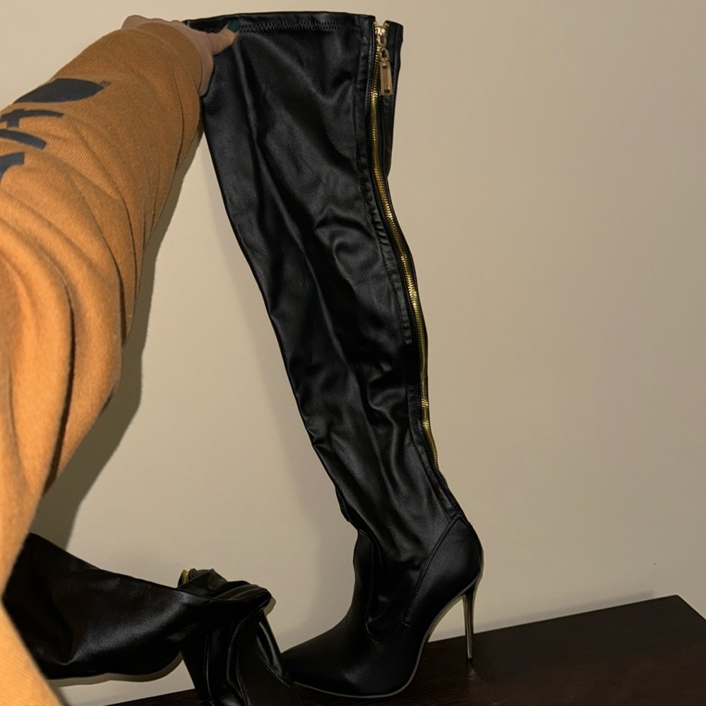 Black leather thigh high boots, gold heel, never worn. Size 8.5 possibly